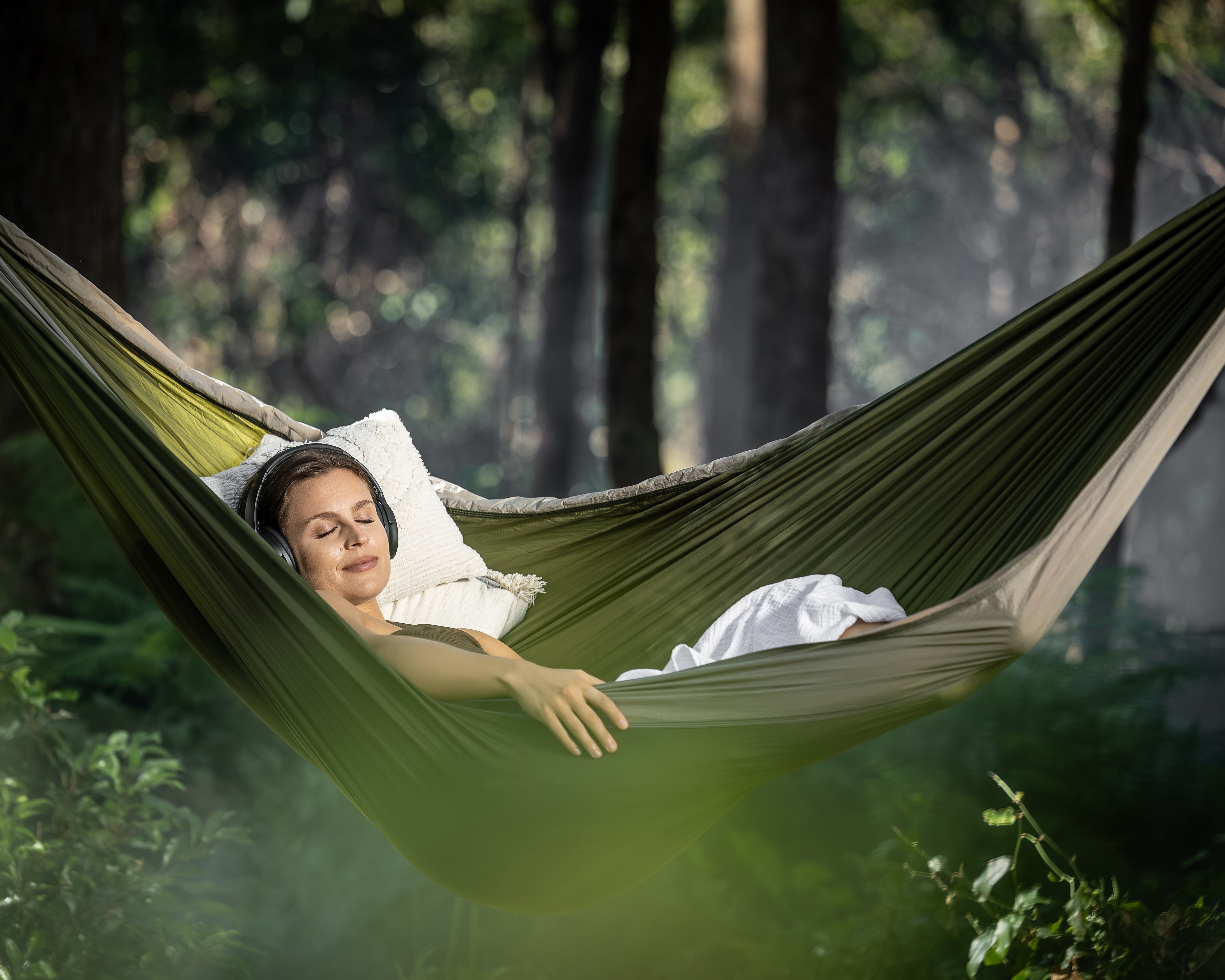 Person relaxing in a green hammock surrounded by trees